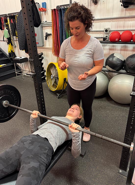 Woman Bench Pressing with another woman ready to spot