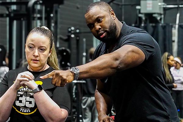 Lee Boyce providing hands-on training to female student at gym