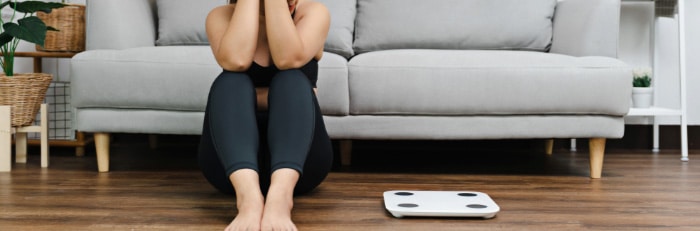 Woman sitting on floor beside a scale